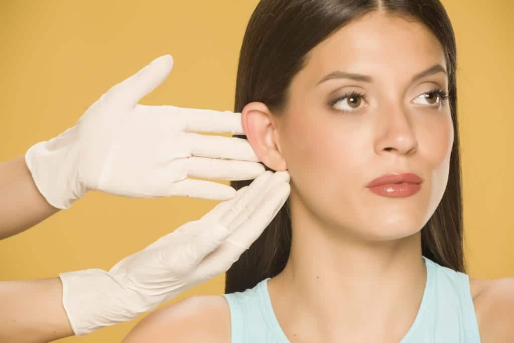 close up of doctor with gloves inspecting woman's ear